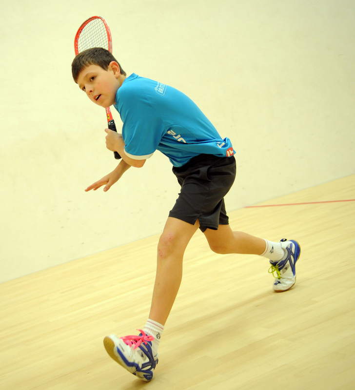 A junior squash player swings his racket on the squash court in DC