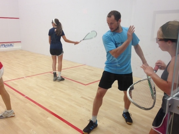 Photo of Greg Gaultier instructing juniors squash players on a squash court at Squash Revolution